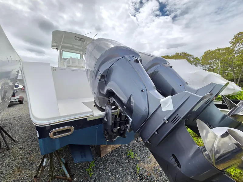 Slide: The Image of 2005 Regulator 32 Forward Seating boat with dual outboard motors, parked on gravel. - 4