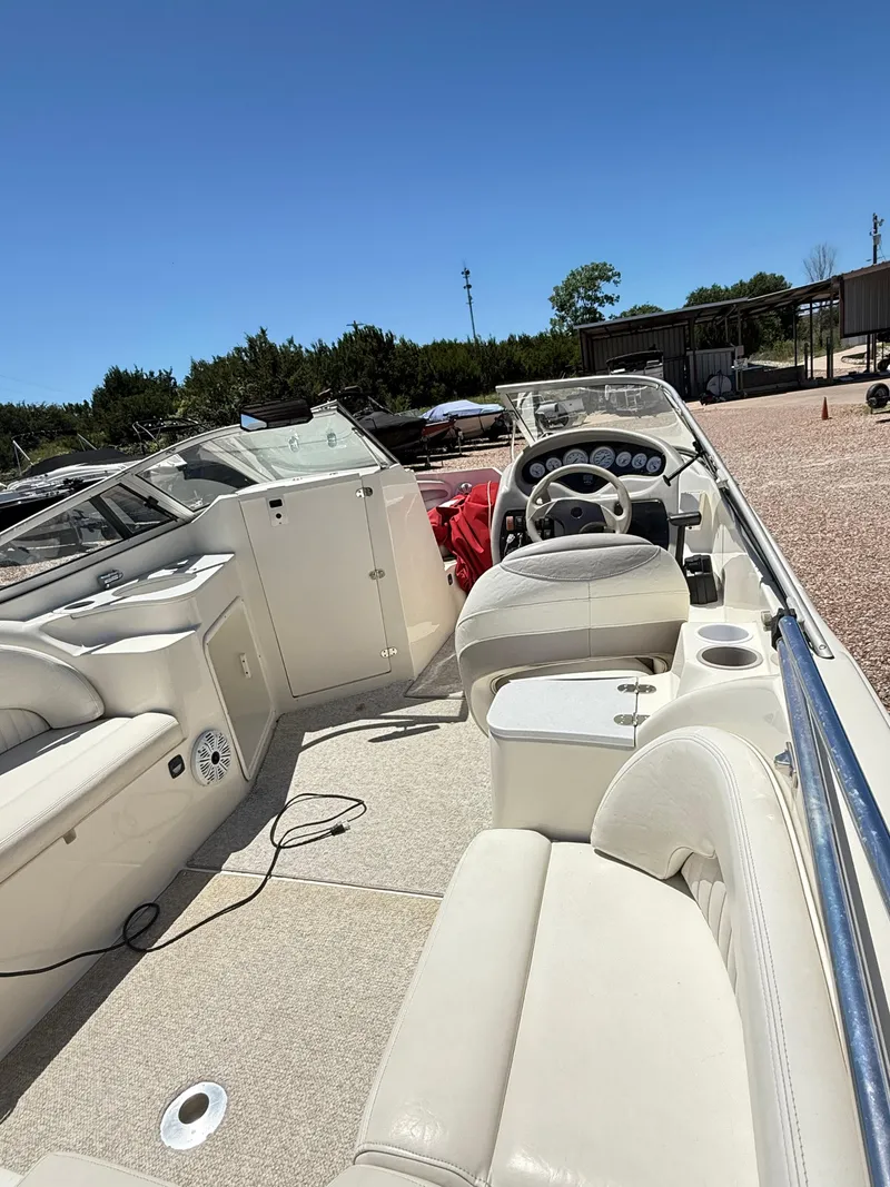 Slide: The Image of 2005 Stingray 220 DR boat interior with steering wheel and seating under clear blue sky. - 14