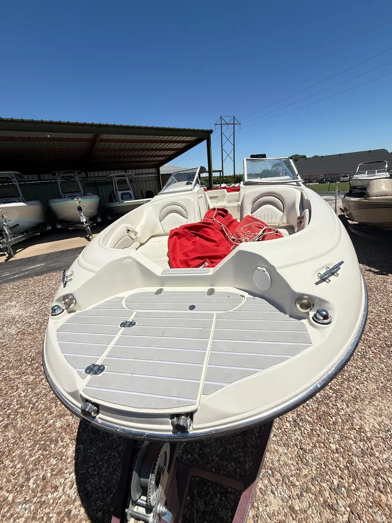 Slide: The Image of 2005 Stingray 220 DR boat with red cover, parked outdoors under clear blue sky. - 3