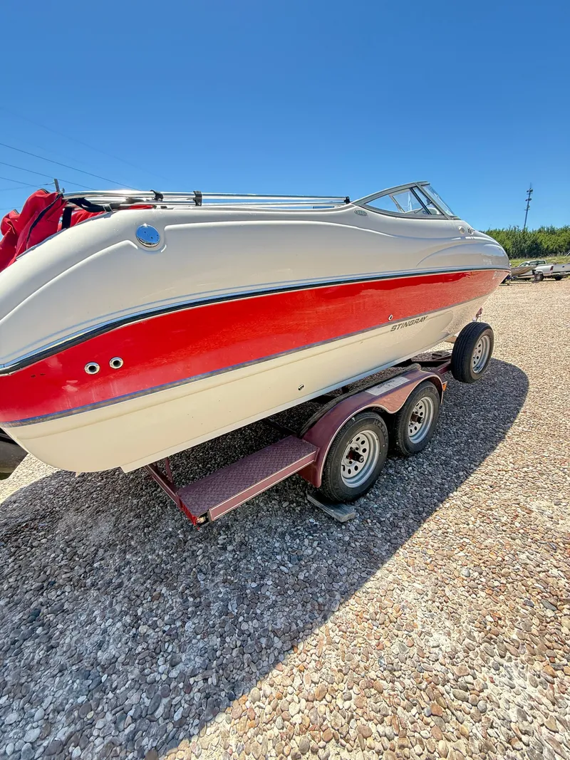 Slide: The Image of 2005 Stingray 220 DR boat on trailer, red and white design, parked on gravel. - 5