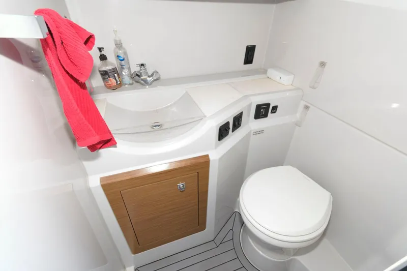 Slide: The Image of 2020 Cruisers Yachts 338 SS OB bathroom with sink, toilet, and red towel. - 17