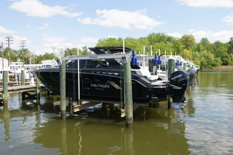 Slide: The Image of 2020 Cruisers Yachts 338 SS OB docked on a lift, surrounded by water and trees. - 2