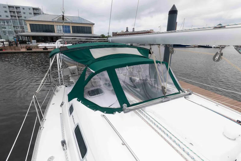 Slide: The Image of 2003 Beneteau 393 sailboat docked, featuring green canopy and sleek design. - 13