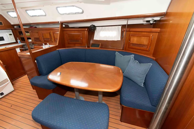 Slide: The Image of 2003 Beneteau 393 yacht interior with wooden dining area and blue cushioned seating. - 15