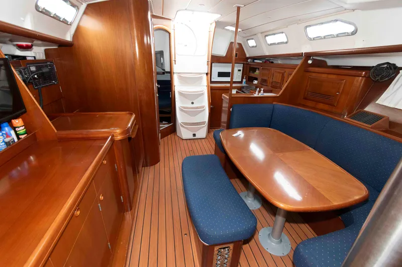 Slide: The Image of Interior of 2003 Beneteau 393 yacht with wooden furnishings and blue seating. - 16
