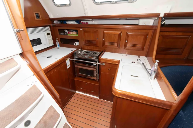 Slide: The Image of Compact kitchen in a 2003 Beneteau 393 sailboat with wood cabinetry and appliances. - 17