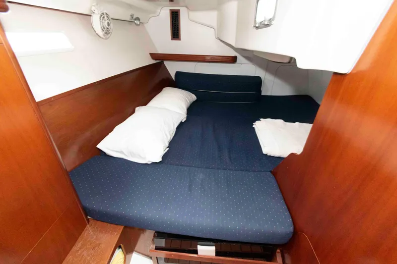 Slide: The Image of Cozy cabin interior of 2003 Beneteau 393 sailboat with blue bedding and wooden accents. - 19
