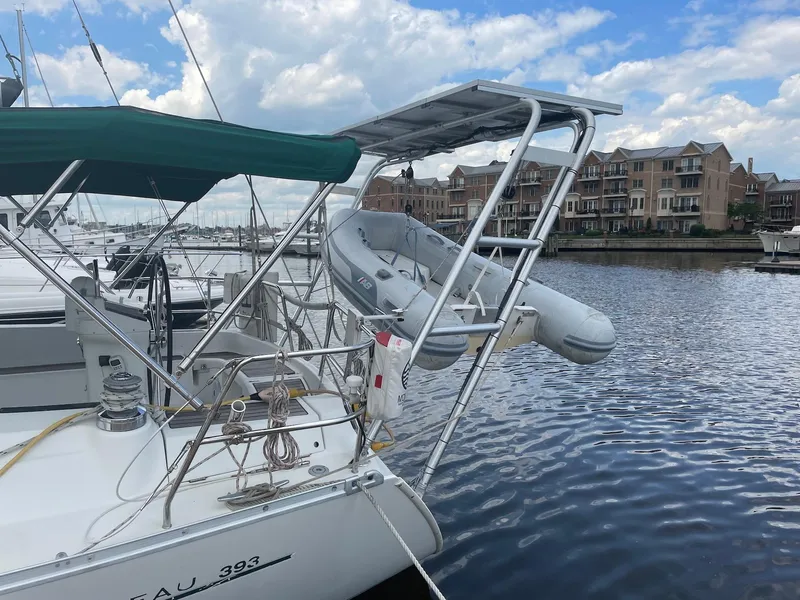 Slide: The Image of Beneteau 393 sailboat docked, featuring a dinghy and waterfront buildings in the background. - 7