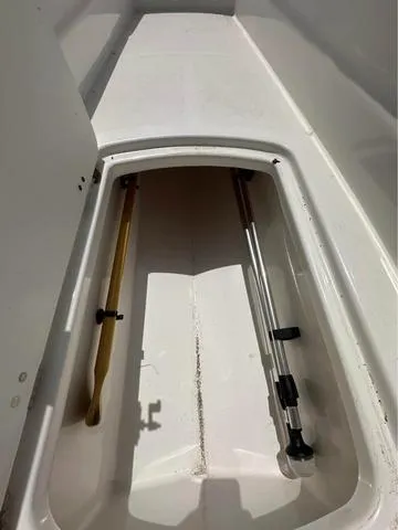 Slide: The Image of Storage compartment in a 2022 Tracker T16 boat, featuring a paddle and pole. - 15
