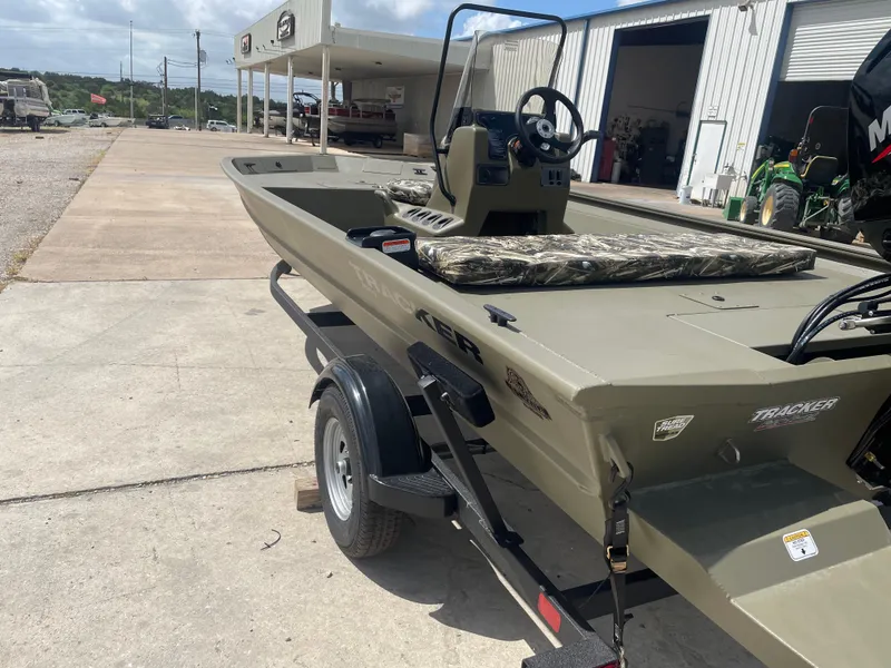 Slide: The Image of 2025 Tracker Grizzly 1860 CC boat on trailer, parked outside a garage. - 4