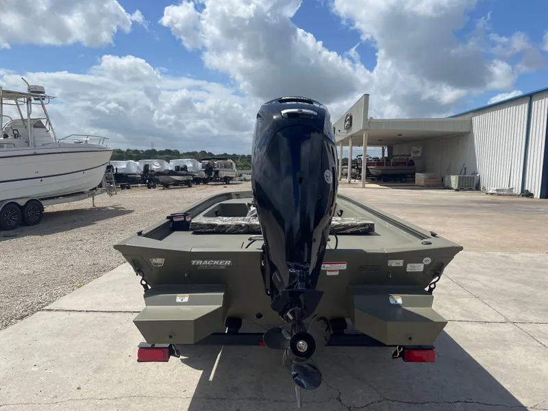 Slide: The Image of 2025 Tracker Grizzly 1860 CC boat with outboard motor, parked outdoors under a cloudy sky. - 5