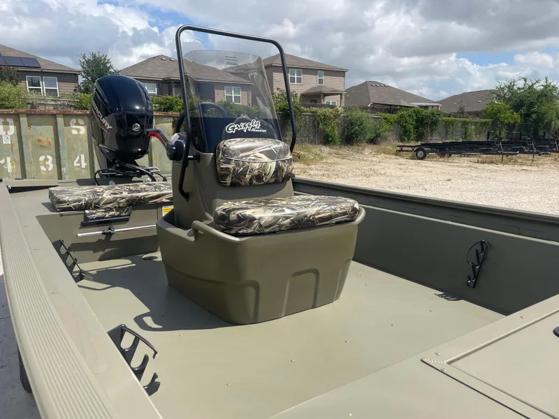 Slide: The Image of 2025 Tracker Grizzly 1860 CC boat with camouflage seats, parked outdoors under cloudy skies. - 8