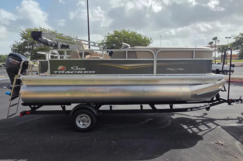 The Image of 2025 Sun Tracker Party Barge 18 DLX pontoon boat on trailer, parked outdoors. - 0