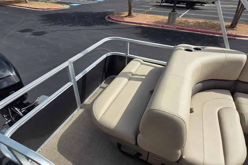 Slide: The Image of 2025 Sun Tracker Party Barge 18 DLX with beige seating and railing in a parking lot. - 10
