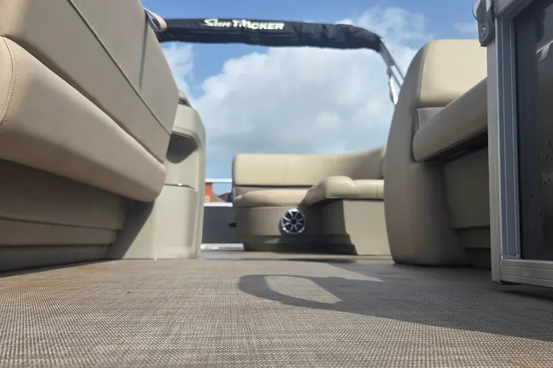 Slide: The Image of 2025 Sun Tracker Party Barge 18 DLX interior with beige seating and open deck view. - 8
