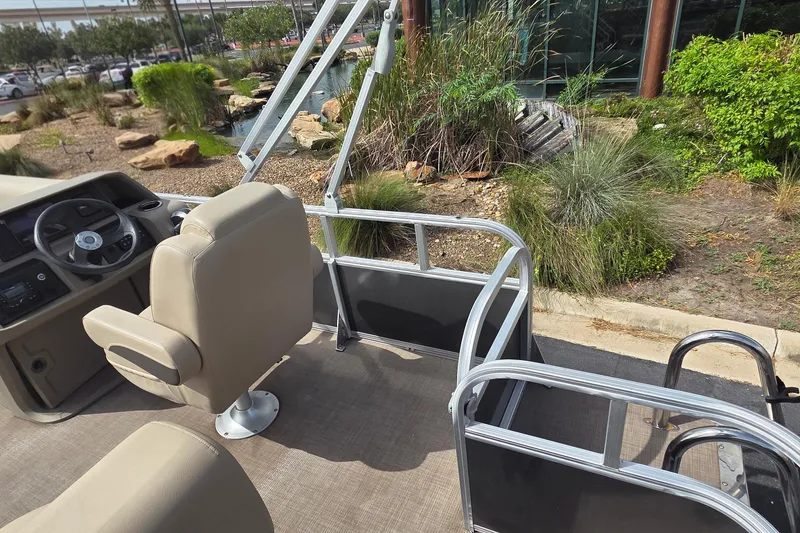 Slide: The Image of 2025 Sun Tracker Party Barge 18 DLX interior with beige seating and steering console. - 6