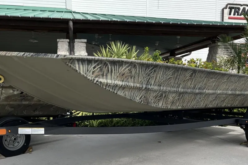 The Image of 2025 Tracker Grizzly 1860 Utility boat with camouflage design on a trailer. - 0