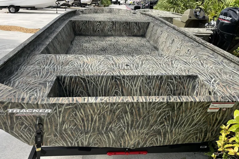 Slide: The Image of 2025 Tracker Grizzly 1860 Utility boat with camouflage design, parked outdoors. - 2