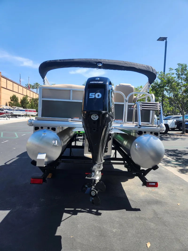 Slide: The Image of 2025 Sun Tracker Party Barge 16 DLX pontoon boat with 50 HP engine in parking lot. - 2
