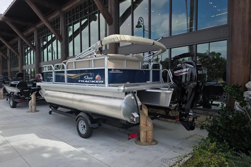 Slide: The Image of 2025 Sun Tracker Bass Buggy 16 XL Select pontoon boat displayed outdoors. - 4