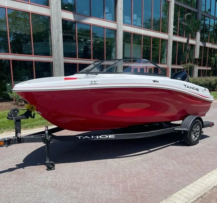 Slide: The Image of 2025 Tahoe 185 S boat with red hull on trailer, parked outdoors. - 2