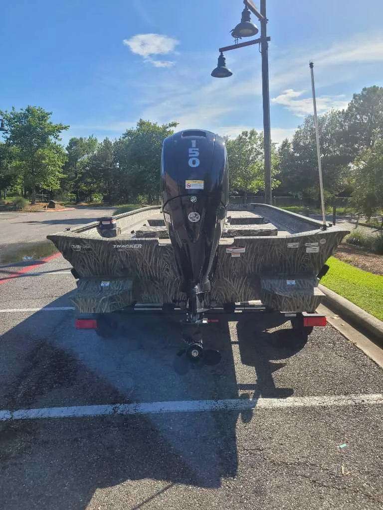 Slide: The Image of 2025 Tracker Grizzly 2072 CC boat with 150 HP engine in a parking lot. - 2