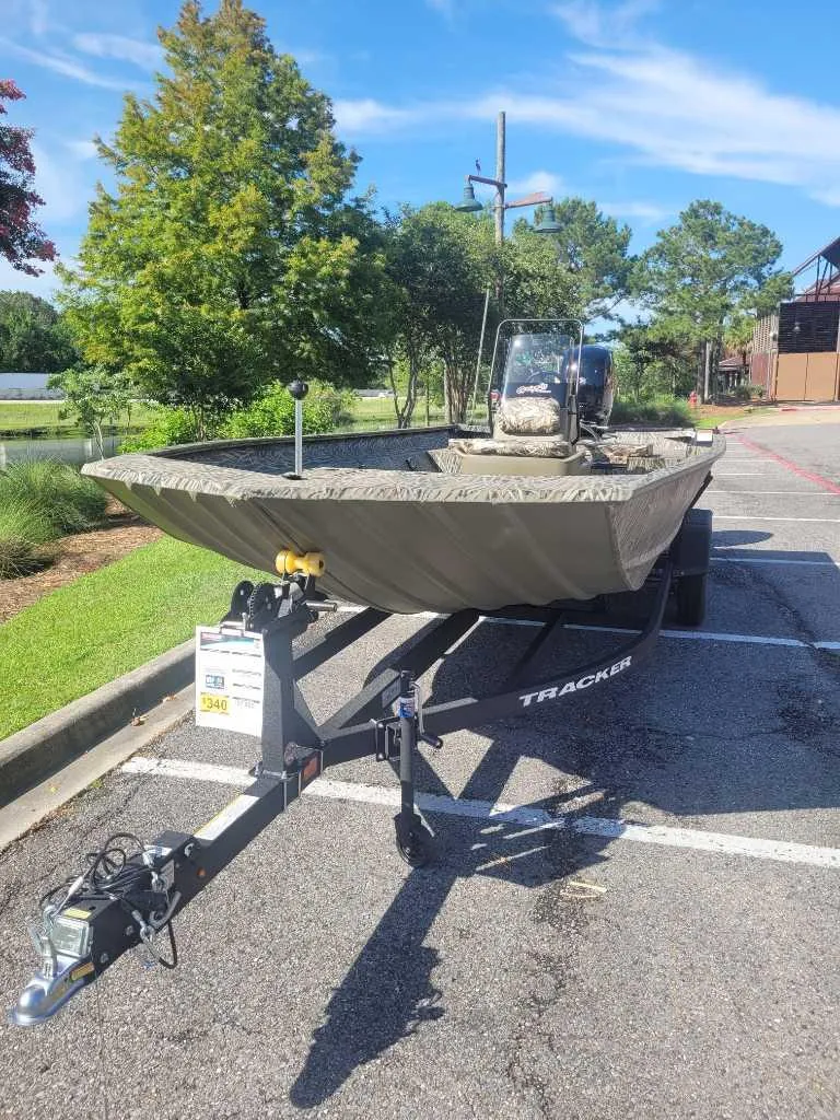 Slide: The Image of 2025 Tracker Grizzly 2072 CC boat on trailer in parking lot, surrounded by trees. - 5