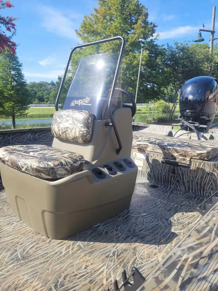 Slide: The Image of 2025 Tracker Grizzly 2072 CC boat with camo seats and console, outdoors in a scenic setting. - 7