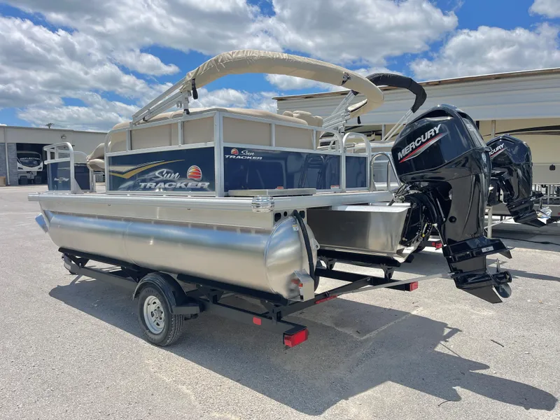 Slide: The Image of 2025 Sun Tracker Bass Buggy 16 XL Select pontoon boat with Mercury engine on trailer. - 2