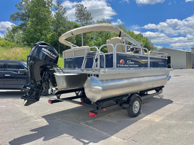 Slide: The Image of 2025 Sun Tracker Bass Buggy 16 XL Select pontoon boat on trailer, outdoors. - 3