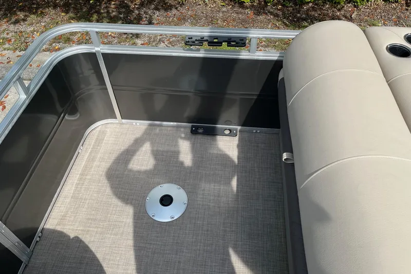 Slide: The Image of 2025 Sun Tracker Fishin' Barge 20 DLX interior with beige seating and metal railing. - 12