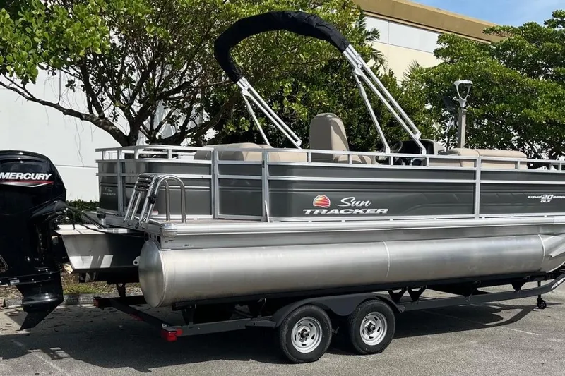 Slide: The Image of 2025 Sun Tracker Fishin' Barge 20 DLX pontoon boat on trailer, parked outdoors. - 3