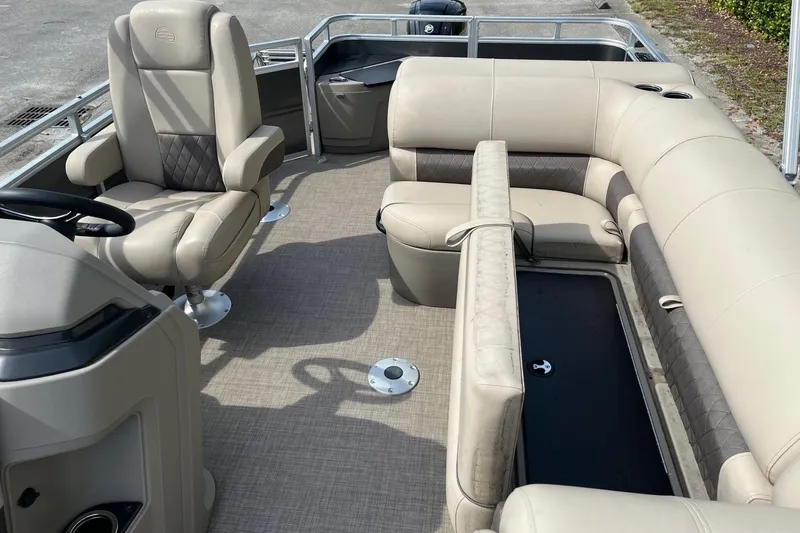 Slide: The Image of 2025 Sun Tracker Fishin' Barge 20 DLX interior with beige seating and steering console. - 9