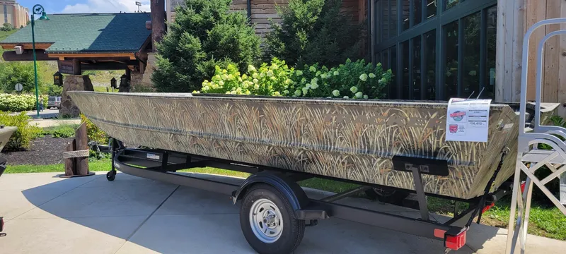 The Image of 2025 Tracker GRIZZLY 2072 Utility boat with camouflage design on a trailer outdoors. - 0