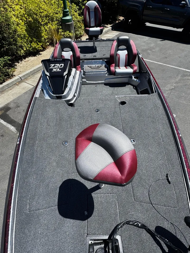 Slide: The Image of 2025 Nitro Z20 XL Pro fishing boat with red and gray seats in a parking lot. - 2