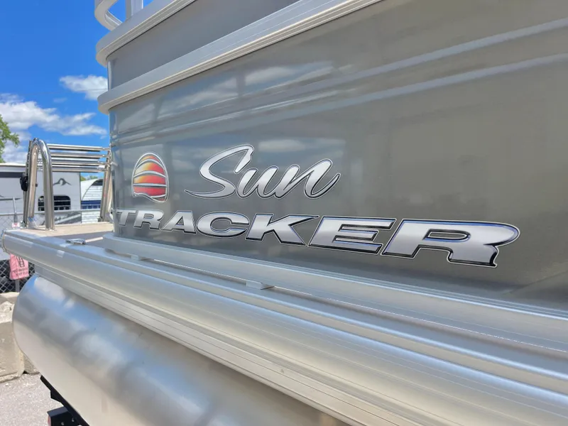 Slide: The Image of 2025 Sun Tracker Party Barge 20 DLX pontoon boat with logo, sunny day background. - 14