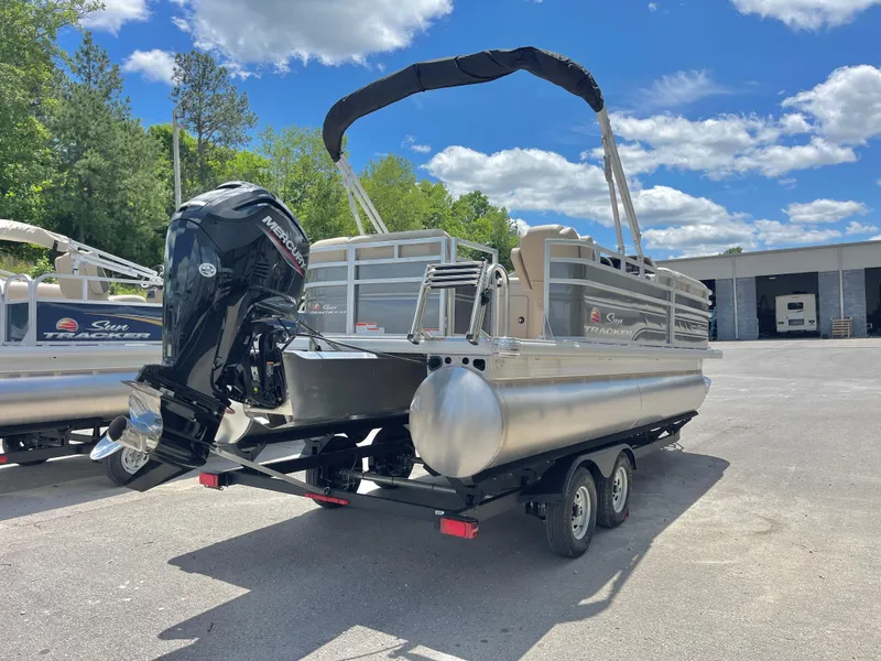 Slide: The Image of 2025 Sun Tracker Party Barge 20 DLX pontoon boat on trailer, parked outdoors. - 2