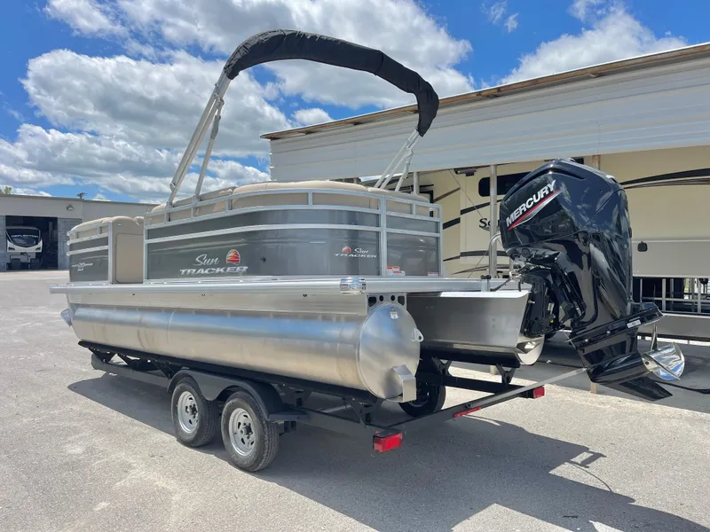 Slide: The Image of 2025 Sun Tracker Party Barge 20 DLX pontoon boat on trailer, parked outdoors. - 3