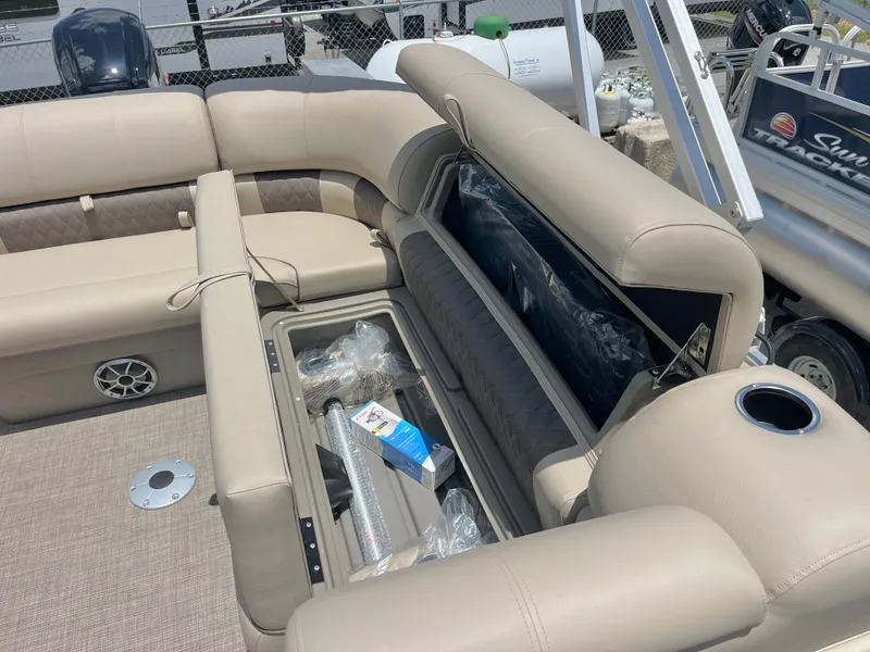 Slide: The Image of 2025 Sun Tracker Party Barge 20 DLX interior with open storage compartment and beige seating. - 9