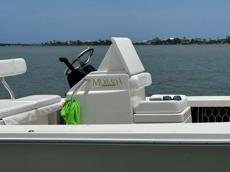 Slide: The Image of 2024 Islamorada Boatworks Morada 18 on calm water, featuring steering console and seating. - 7