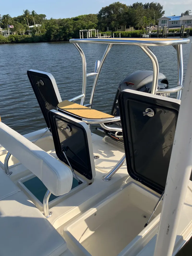 Slide: The Image of 2024 Islamorada Boatworks Morada 18 with open storage compartments, docked by a scenic waterfront. - 8