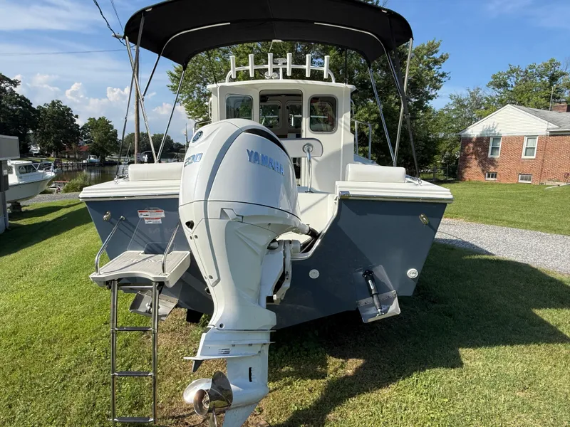 Slide: The Image of Parker 2120 Sport Cabin 2025 boat with Yamaha engine, parked on grass. - 4