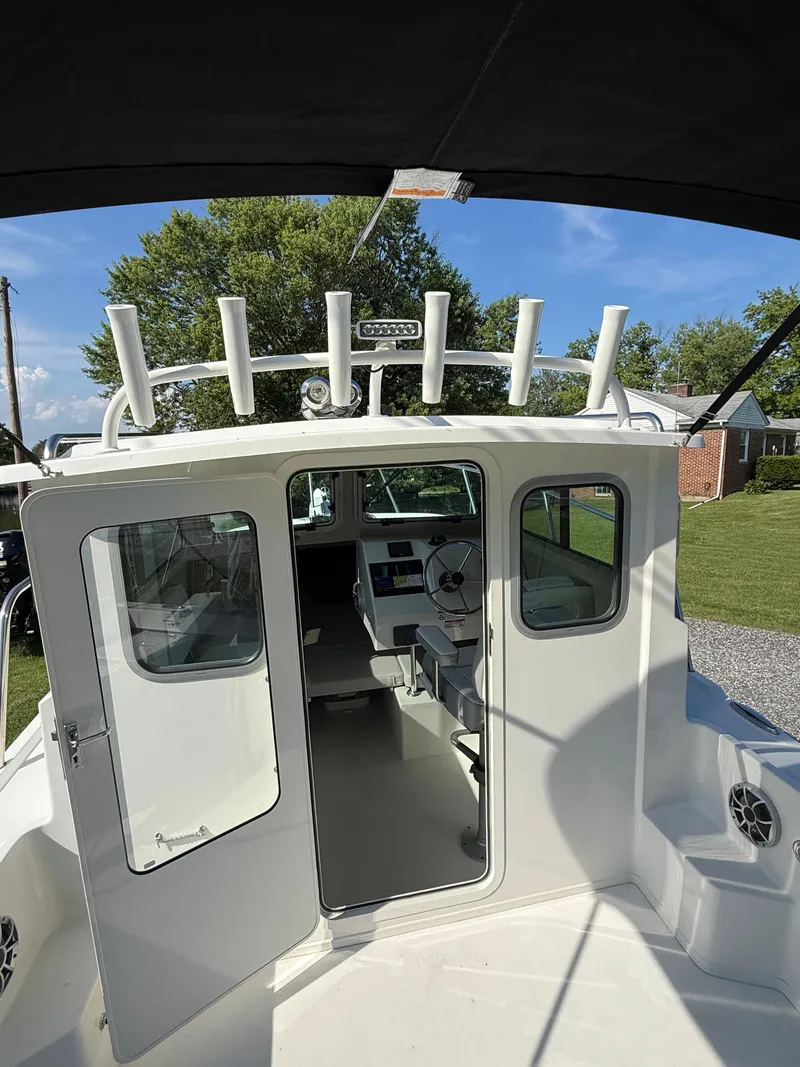 Slide: The Image of 2025 Parker 2120 Sport Cabin boat with open cabin doors, showcasing interior and steering wheel. - 7