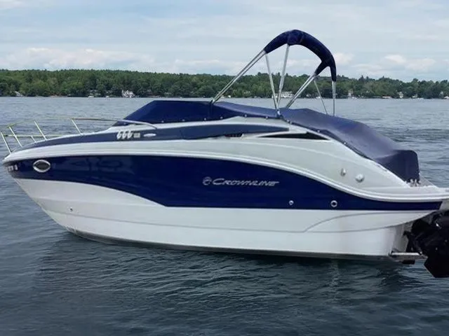 Slide: The Image of 2015 Crownline 264 CR boat on a lake with a blue and white exterior. - 2