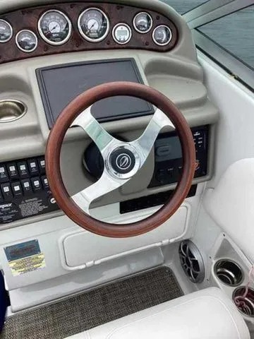 Slide: The Image of 2015 Crownline 264 CR boat dashboard with wood-trimmed steering wheel and control panel. - 8