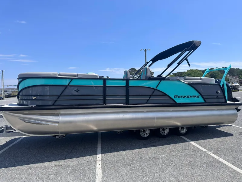 Slide: The Image of 2025 Berkshire 23RFX STS 3.0 pontoon boat with teal and gray design, parked outdoors. - 2