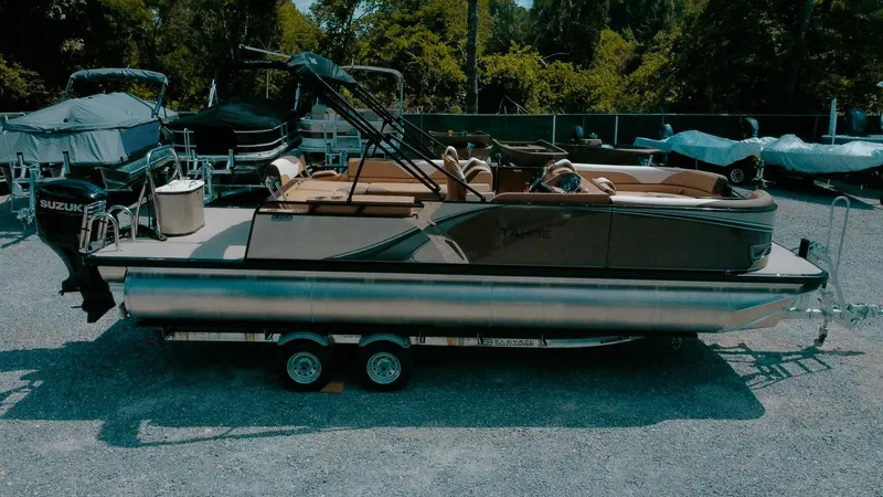 Slide: The Image of 2025 Tahoe Pontoon LTZ Cruise Rear Bench on trailer, parked outdoors. - 1