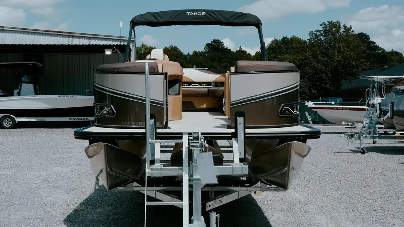 Slide: The Image of 2025 Tahoe Pontoon LTZ Cruise Rear Bench on trailer, parked outdoors. - 10