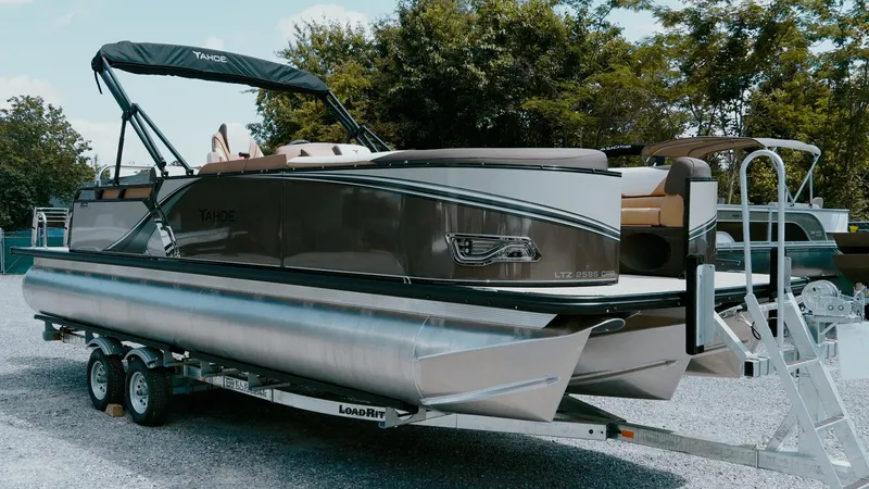 Slide: The Image of 2025 Tahoe Pontoon LTZ Cruise Rear Bench on trailer, parked outdoors. - 8