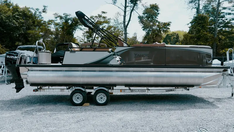 Slide: The Image of 2025 Tahoe Pontoon LTZ Cruise Rear Bench on trailer, parked outdoors. - 9